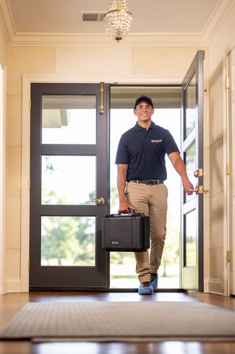Tech walking into a home with an assessment kit ready to help with water damage.
