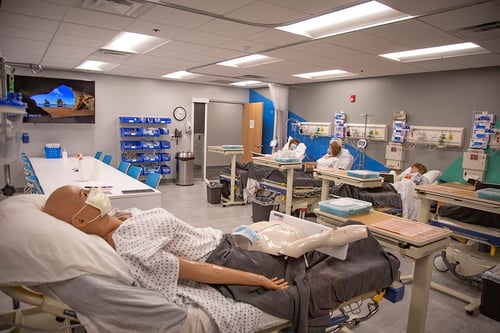 Four high-fidelity patient simulators dressed in hospital gowns, each lying in a hosplital bed located in Joyce University Campus skills lab.
