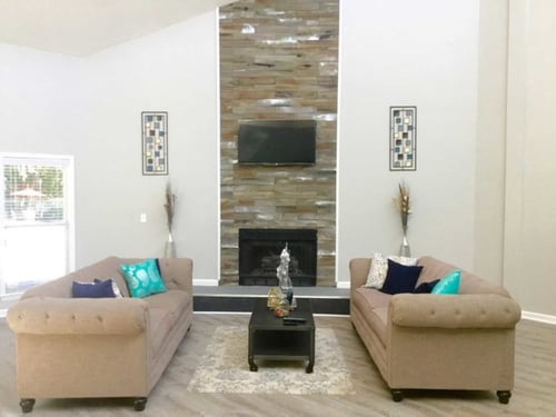 Living room with two beige sofas facing a stone fireplace and television.