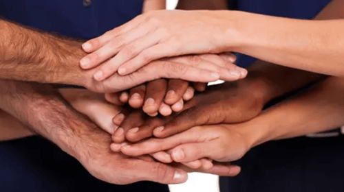 several people putting their hands on top of each other