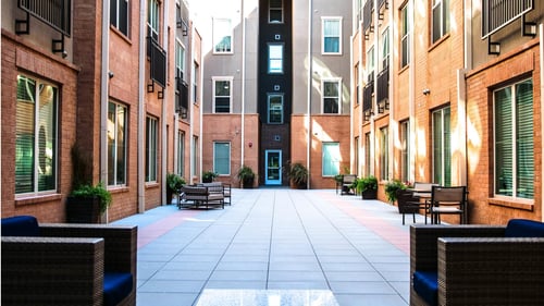 A courtyard with a bench and a table in the middle surrounded by buildings at The Maywood, Oklahoma City, OK, 73104