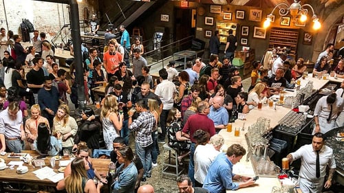 A large group of people eating and drinking inside of Houston Hall.