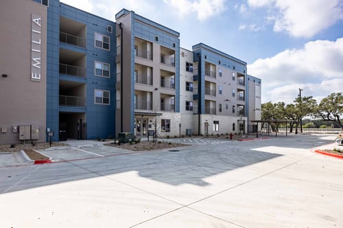 Apartment complex named Emilia with a parking lot in front at Emilia Apartments in Boerne, TX, 78006