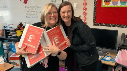 two instructors holding the course curriculum folders