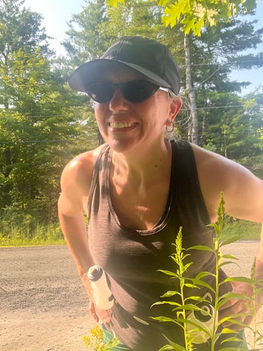 Picture of Colleen on a sunny day standing behind plants