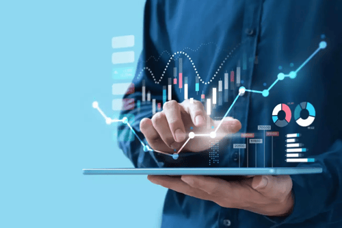 A professional holding a tablet with an overlay of financial graphs.