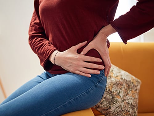 woman sitting on couch experiencing hip pain