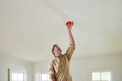man installing a detector in the ceiling