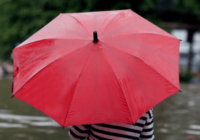 person holding umbrella surveying floodwaters