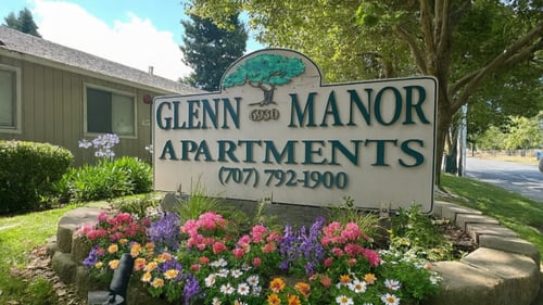 A sign for Glenn Manor Apartments is surrounded by flowers