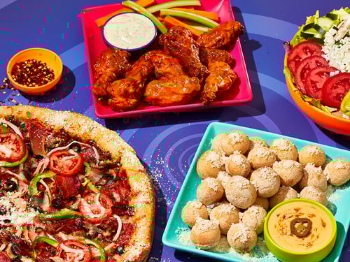 Mellow Mushroom food spread including chicken wings, pizza, pretzel bites and a salad