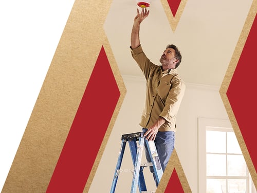 A graphic of an X Cut-out, with a photo of a contractor reaching to remove the dust cover of a smoke alarm.