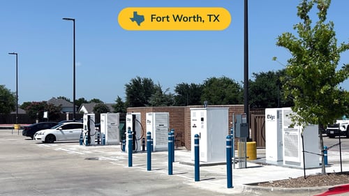 Several EVgo fast charging units installed in marked parking spaces at a public charging station, with EVgo logos on the chargers, protective bollards around each unit