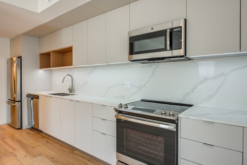 A modern kitchen with a stainless steel refrigerator, microwave, and oven at Prizma in Los Angeles, CA