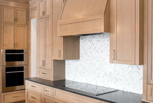 wood cabinets with white backsplash and black counter tops
