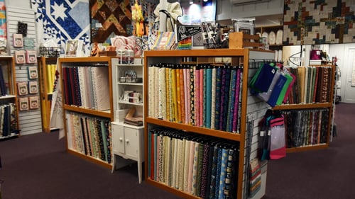 Large shelf with various colored fabrics on it