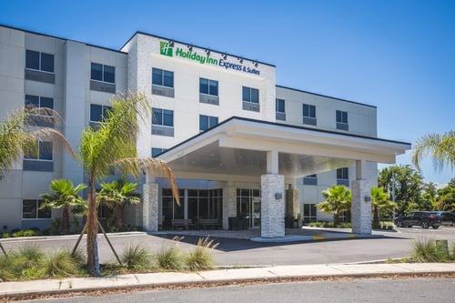 Hotel exterior with covered entrance canopy and palm trees