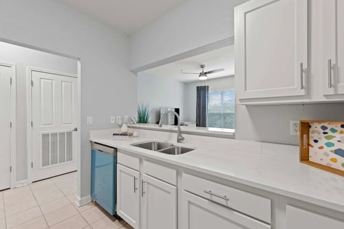A kitchen with white cabinets and a blue trash can at Elan Apartments in Fort Walton Beach, FL