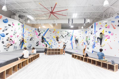 A photo of the Central Rock Gym Citrus Park location. People are bouldering and sitting on the benches.
