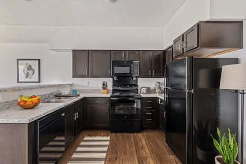 7850 East Jefferson - Modern kitchen with dark wood cabinets, black appliances, and granite countertops