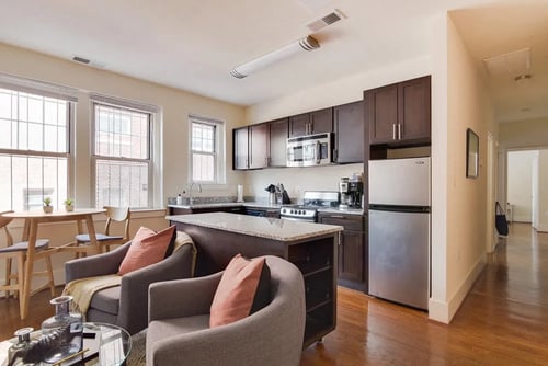 Living and Kitchen Area featuring hardwood floors, ample lighting, stainless steel appliances and a granite island at 1841 Columbia Road Apartments in Washington, DC
