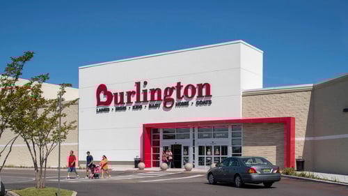 Dark grey car behind people walking in front of Burlington entrance at Springdale shopping center