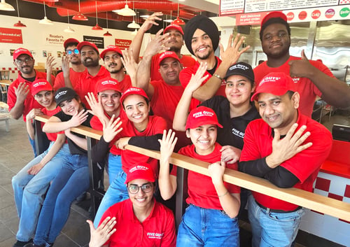 Group of restaurant employees in red uniforms with the text Our Crew. Our Family.