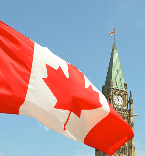 Canadian flag waving in front of the Parliament Building on Parliament Hill in Ottawa.