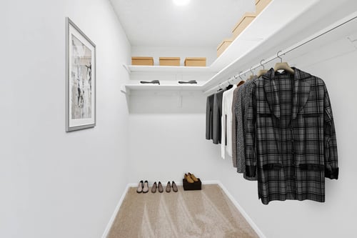 A row of clothes hanging on a rail in a white room.