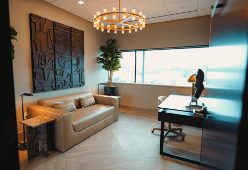 Photo of AirSculpt Birmingham consultation room - couch, sculpture of a body, elegant room with a backlit window