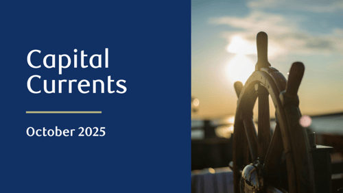 Close-up of a wooden ship steering wheel, with the sun setting over water in the background.