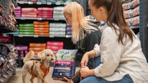 Myyjä esittelee koiranruokaa asiakkaalle