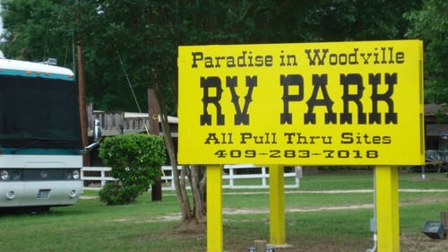 Paradise in Woodville RV Park business sign next to a parked RV