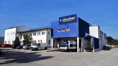 Außenansicht des Firmenstandorts von Ötscher-Berufskleidung mit Gebäudefassade und Unternehmensbeschilderung.
