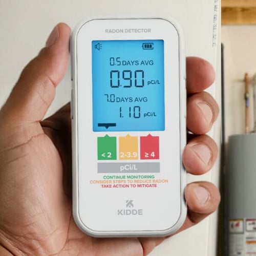 A photo of someone holding the radon detector with their hand.