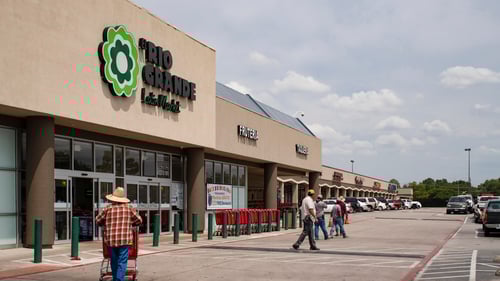 person in straw hat pushing shopping cart towards Rio Grande Latin Market at Webb Royal Plaza shopping center