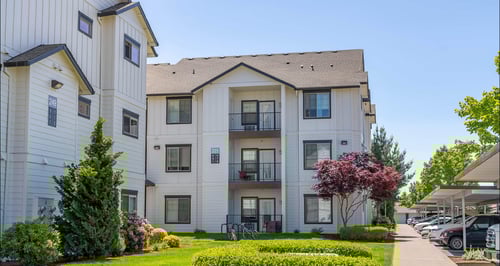 A white apartment building with a green lawn in front at Riverplace Apartment Homes, Independence, OR, 97351