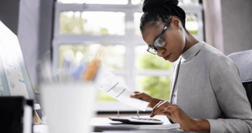 Woman calculating taxes and budgeting with laptop and paperwork for a tax-efficient financial plan