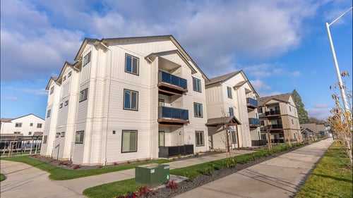 Apartment complex with a green dumpster in front at Woodburn Place Apartment Homes, Oregon