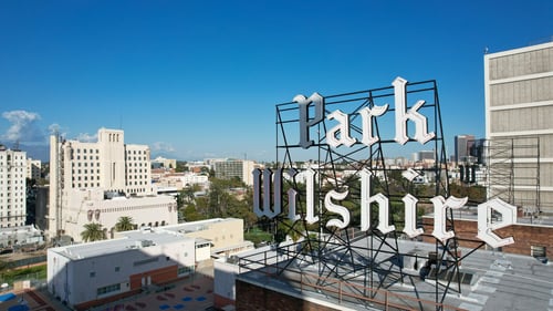 A large sign that says Parkshire is in front of a city skyline at Park Wilshire, Los Angeles, CA, 90057