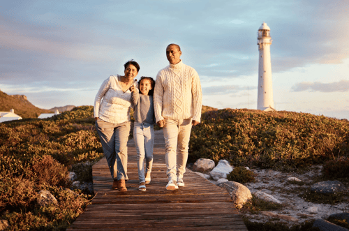 Grandparents with granddaughter on boardwalk in front of lighthouse