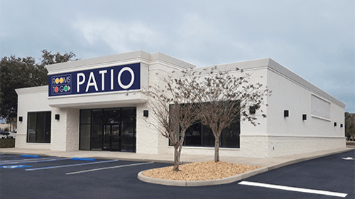 Exterior view of the Rooms To Go Patio Furniture Store in Lakeland, FL, featuring a modern white building with large windows, blue signage, and accessible parking.