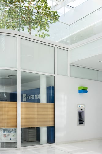Schrägansicht des Bankomaten aus mittlerer Entfernung, die den gesamten Automaten und den umgebenden Bereich umfasst.