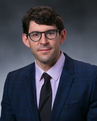 Dr. Peter White in front of a gray background.