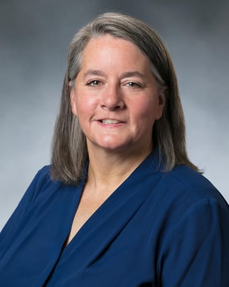 Dr. Elizabeth Day smiling in front of a gray background.