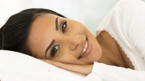 A smiling woman laying down on her hands