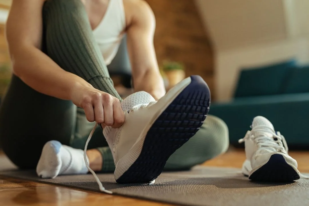 woman putting on athletic shoes for arch support