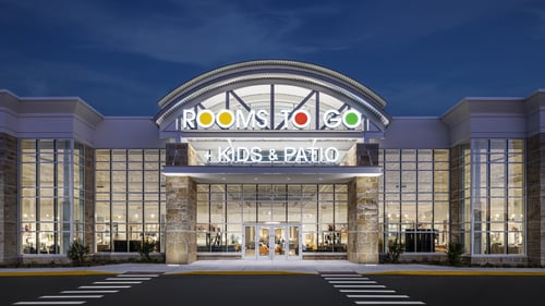 Exterior of the Rooms To Go store in Clearwater, Florida, at night, featuring illuminated signage and large glass windows showcasing the Kids & Patio sections.