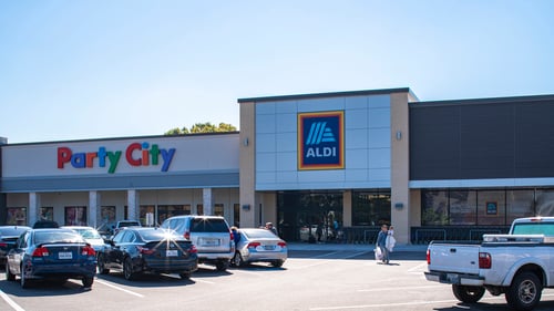People walking through full parking lot in front of Party City and Aldi at Tanglewilde Shopping Center