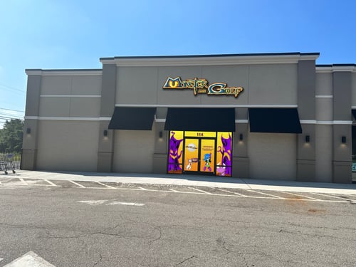 A building with a sign that says ‘Monster Mini Golf’ in yellow and purple letters. The entrance has colorful cartoon-style monster graphics.